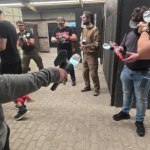 Groep deelnemers met glow gel blasters tijdens een vrijgezellenfeest in de indoor arena.