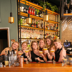 groep-poseert-met-cocktails-achter-de-bar