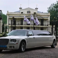 Witte Big Limo trouwlimousine met bloemstuk voor een statige locatie