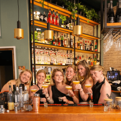 groep-poseert-met-cocktails-achter-de-bar
